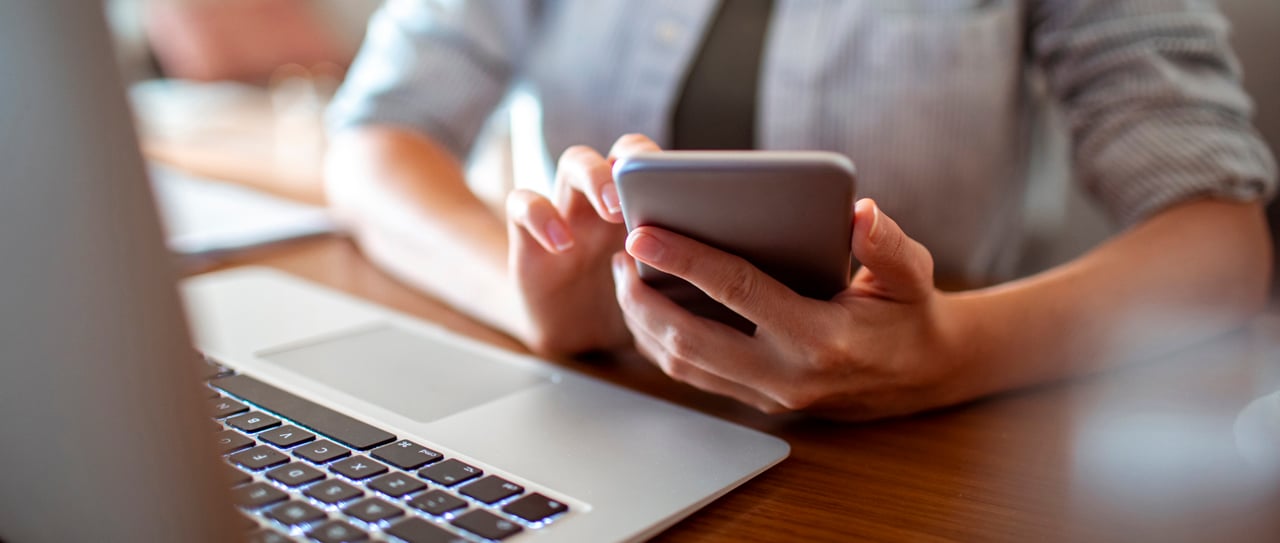 Someone using an aluminium smartphone and laptop