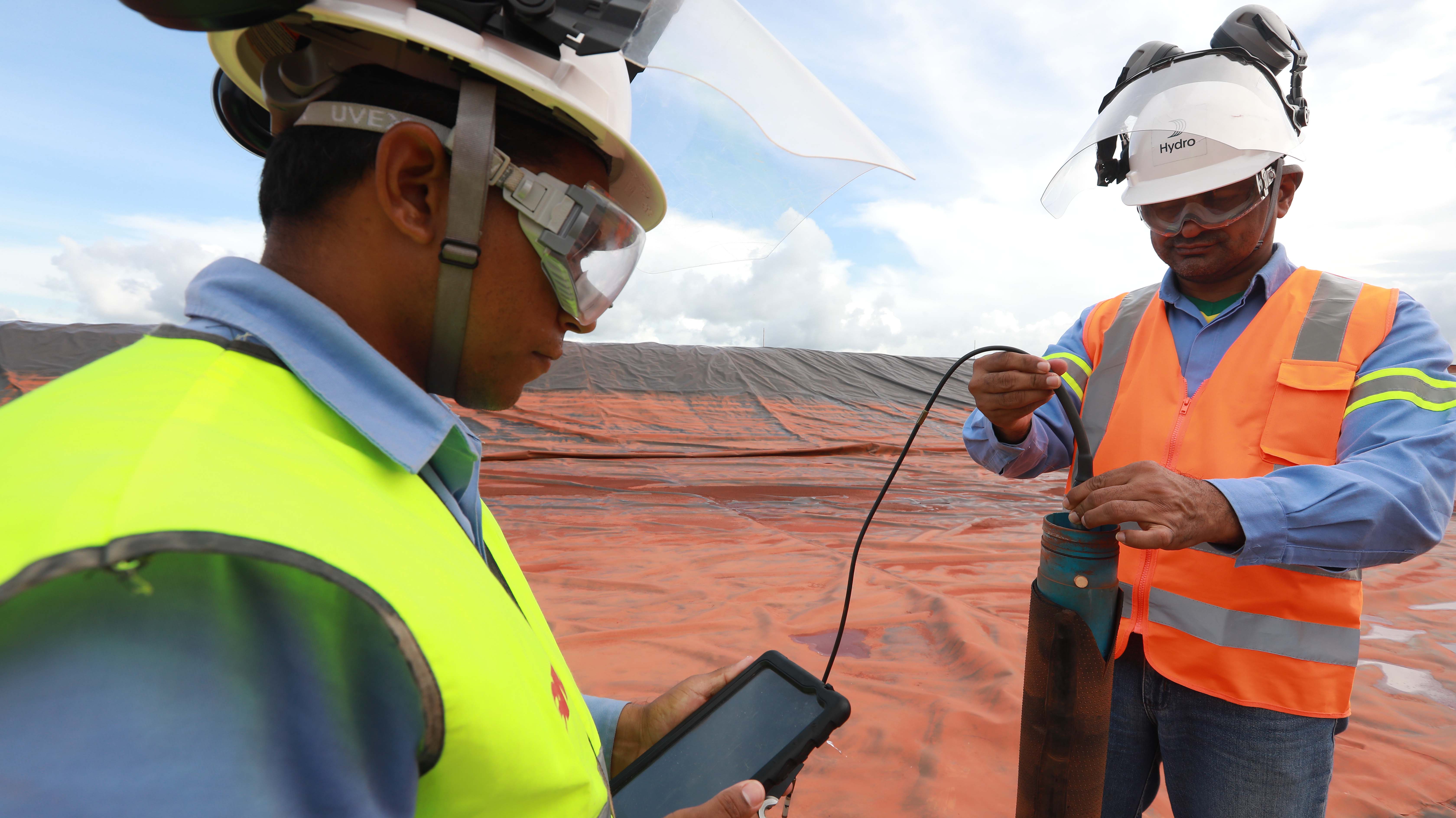 a few men in hardhats looking at a piece of wood