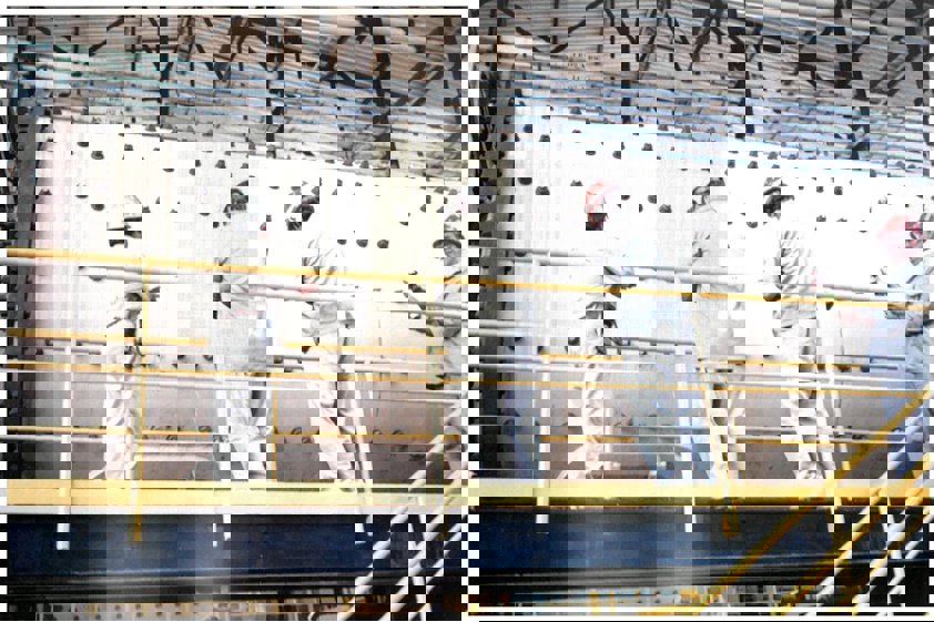 a group of people in white protective gear working on a metal frame